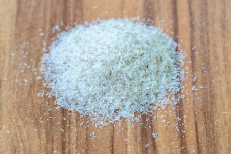 Psyllium husk isolated on wooden background. It's a common home remedy for constipation and other health issues. The husk of the Plantago ovata plant is also known as ispaghula husk, or isabgol husk