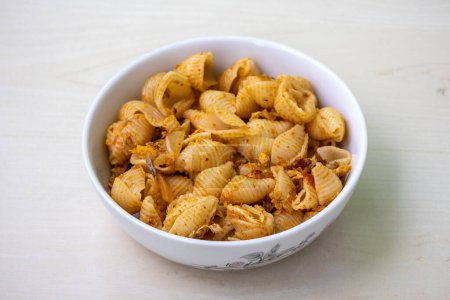 Delicious shell pasta in a white bowl on wooden background
