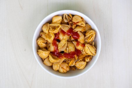 Delicious shell pasta with tomato sauce in a white bowl on wooden background. Top view of tasty conchiglie rigate pasta.