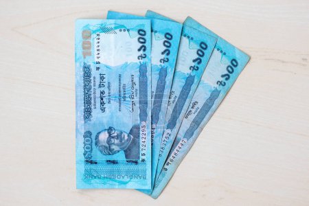 Bangladeshi currency BDT 100 taka note isolated on wooden background.