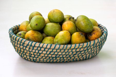 Heaps of fresh ripe mangoes on a basket. A Beautiful handmade wicker basket filled with ripe mangoes.