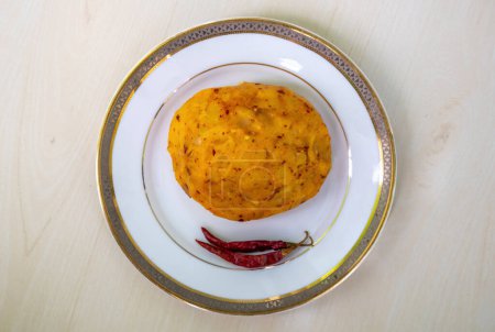Delicioso Alu Bharta en un plato blanco sobre un fondo de madera. Aloo Bhorta es la comida más simple y tradicional de Bangladesh y la región de Bengala de la India. Vista superior.