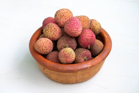 Una olla de barro llena de deliciosos lichis maduros. Los lichis tienen una piel de textura marrón rojiza. Los lichis son una fruta tropical saludable.