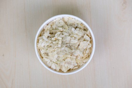 Abgeflachter Reis oder Chira auf einer weißen Schüssel auf einem hölzernen Hintergrund. Es ist auch als pohe, aval, pauwa, sira, chivda oder avalakki bekannt.