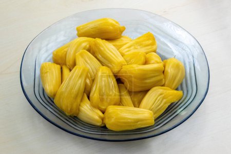 Delicious jackfruit on a glass plate on wooden background. Jakfruit is a healthy tropical fruit.