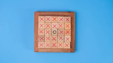Wooden game board tic-tac-toe. Turning of the letters X-O and middle one different from each other on blue background.