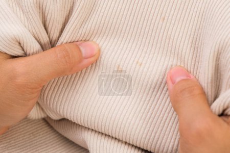 Photo for Close-up of woman looking at dirty stains on child's unwashable shirt. Dissatisfied young woman showing stains on t-shirt. Laundry problems - Royalty Free Image