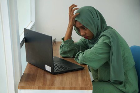 Foto de Una mujer musulmana que trabaja en casa usando un portátil - Imagen libre de derechos