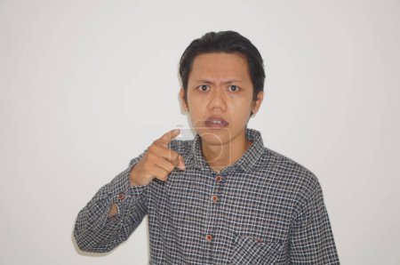young asian man wearing black shirt angry by pointing at camera