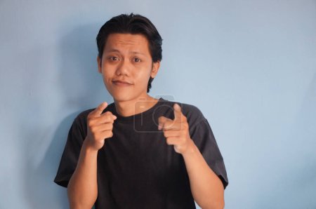 Joven asiático hombre vistiendo negro camiseta feliz y sonriendo señalando a la cámara