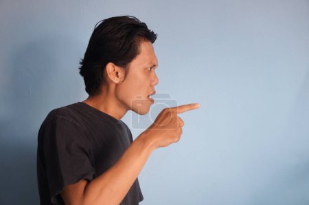 young asian man wearing black shirt angry by pointing at side