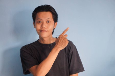 Photo for Young asian man wearing black t-shirt smiling pointing with hand finger to the side - Royalty Free Image