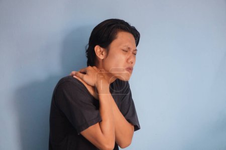 Jeune homme asiatique toucher son épaule avec l'expression de la douleur