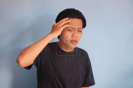 Young Asian man got painful migraine gesture