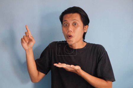 Photo for Young Asian man wearing black t-shirt happy pointing with hand finger up - Royalty Free Image