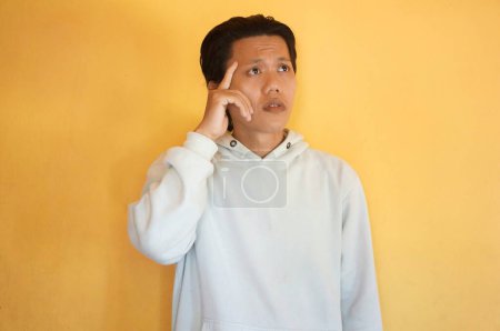 Photo for Asian young man thinking about something. isolated yellow background. - Royalty Free Image
