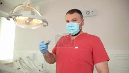 Photo for Professional dentist in red uniform in dental office. - Royalty Free Image