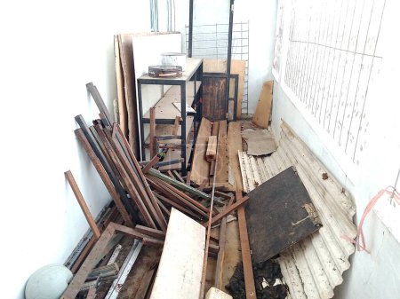 Photo for Photo of a warehouse with white walls, messy storage, various kinds of goods piled up, rusty iron, display cases, wooden boards, plastic, dirty and dusty - Royalty Free Image