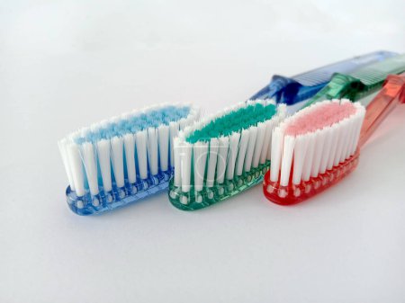 close-up image of three toothbrushes, blue, green and red, isolated on a white background