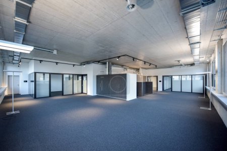 Photo for Modern office space empty with copyspace concrete ceiling and anthrazit carpet, light track in black and a metal ventilation duct - Royalty Free Image