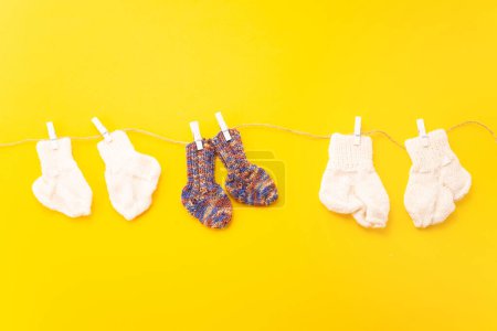 Photo for November 17, World Prematurity Day, Normal size and Tiny socks on rope with yellow background - Royalty Free Image