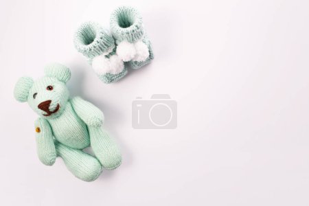  Babysocken und Teddybär auf weißem Hintergrund. Geburt eines Jungen. Grußkarten-Idee für Neugeborene. Schwangerschaftsankündigung. Flachlage, Draufsicht