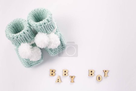 Wort Baby Junge mit Holzbuchstaben auf weißem Hintergrund geschrieben. Babysocken auf weißem Hintergrund. Geburt eines Jungen. Grußkarten-Idee für Neugeborene. Schwangerschaftsankündigung. Flachlage, Draufsicht