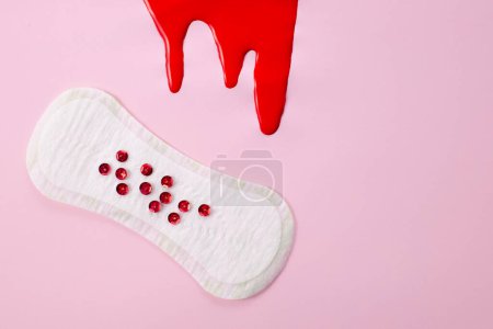 Blut und feminine Hygieneunterlage mit rotem Glitzern auf rosa Hintergrund. Konzept der ersten Menstruationszeit.