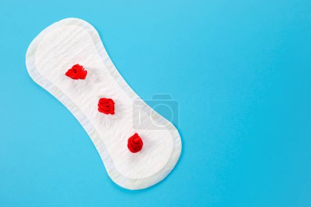 Weibliches Hygienepolster mit roten Blüten auf rosa Hintergrund. Erste Menstruationsperiode Konzept, Menstruationszyklus Periode. Kopierraum
