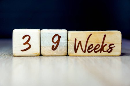 Téléchargez les photos : 39 semaines de grossesse âge jalon écrit sur un cube en bois avec un fond noir - en image libre de droit