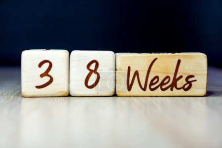 Téléchargez les photos : 38 semaines de grossesse âge jalon écrit sur un cube en bois avec un fond noir - en image libre de droit