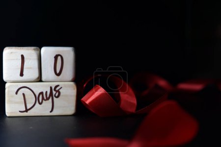 Téléchargez les photos : Jalon de l'âge du bébé écrit sur un cube en bois avec un ruban rouge sur un fond noir - en image libre de droit