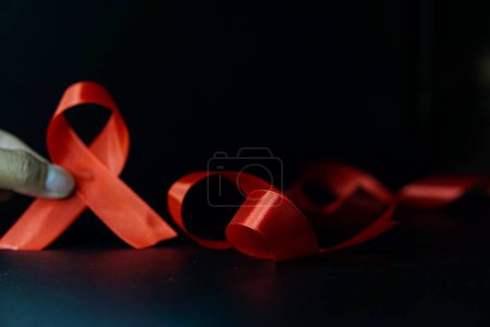 Téléchargez les photos : Mains tenant des rubans rouges pour appuyer le concept de la Journée mondiale du sida et du Mois de la sensibilisation au VIH / sida. - en image libre de droit