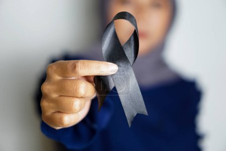Téléchargez les photos : Femme asiatique tenant un ruban noir. Mélanome et cancer de la peau, mois de sensibilisation aux blessures causées par le vaccin et concept de condoléances. - en image libre de droit