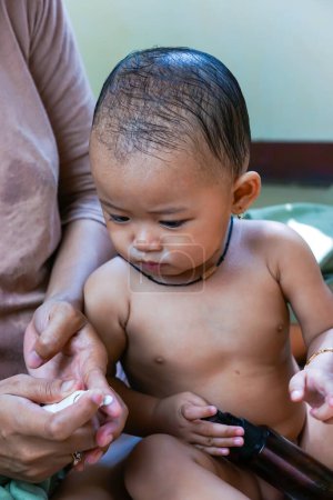 Eine mutter trägt körper creme auf sie süß klein asiatisch baby mädchen