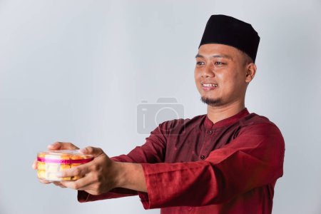 Portrait of an Asian Muslim man holding nastar cookies