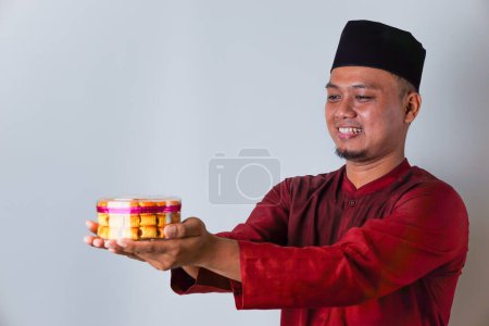 Portrait of an Asian Muslim man holding nastar cookies