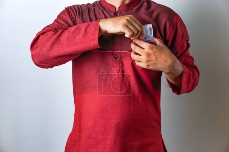 Geste eines asiatischen muslimischen Mannes, der Rupiah-Scheine in seine Tasche steckt