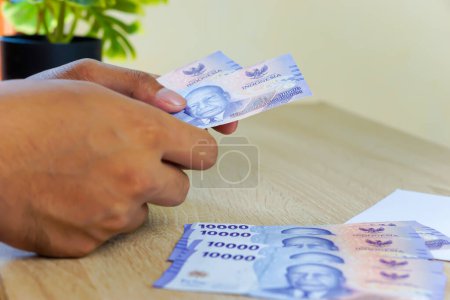 portrait of a hand counting Rupah notes on a table