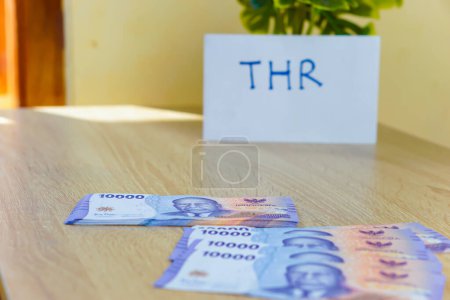 retrato de billetes de Rupah sobre la mesa para THR. THR o Tunjangan Hari Raya es un subsidio de vacaciones o bono dado antes del Ramadán.