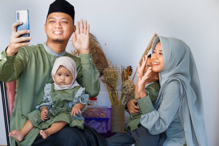 retrato de la familia musulmana feliz y sonriente tomar una selfie juntos o tener una reunión virtual con el teléfono inteligente durante la celebración del ramadán Eid Mubarak.