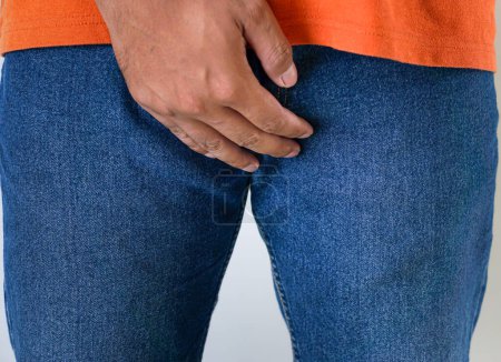 El hombre en jeans se cubre la entrepierna con la mano. concepto de salud de los hombres, problemas urológicos y concepto de disfunción eréctil