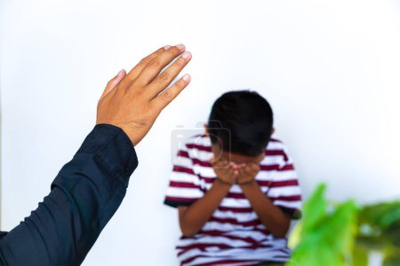 Photo for Violence against children.  Cropped of man raising his hands in anger, a small child crying and covering his face with his hands in the background. - Royalty Free Image
