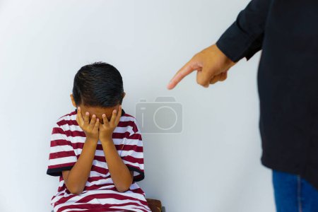 Photo for Violence against children.Cropped of man pointing in anger at a small child who is crying and covering his face with his hands in the background. - Royalty Free Image