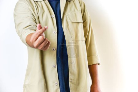 A person in a beige jacket makes popular mini-heart gestures with both hands, symbolizing affection or love.