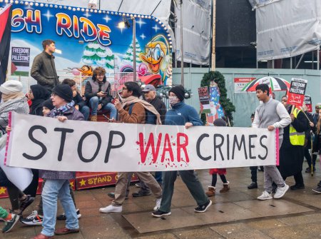 Photo for Protest walk calling for stop war crimes, Southampton, UK, 16 December, 2023. Several individuals are seen marching with a banner that reads "STOP WAR CRIMES" in bold letters. - Royalty Free Image