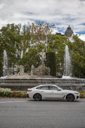 Téléchargez les photos : Madrid, Espagne ; 18-10-2023 : BMW 4 series premium car passant devant la Plaza de Neptuno à Madrid, avec une statue du dieu de la mythologie romaine - en image libre de droit