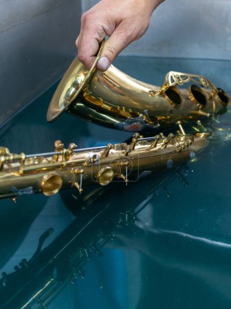 Foto de Inmersión de un saxofón para la limpieza - Imagen libre de derechos