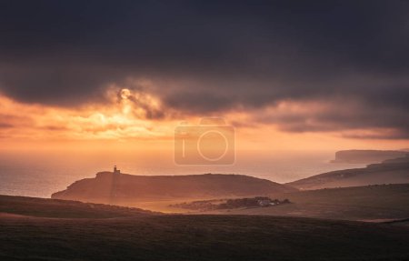 Téléchargez les photos : Ciel et coucher de soleil spectaculaires derrière le phare Belle Tout depuis le bord de la falaise de Beachy Head sur les bas sud est de la côte du Sussex sud-est de l'Angleterre Royaume-Uni - en image libre de droit