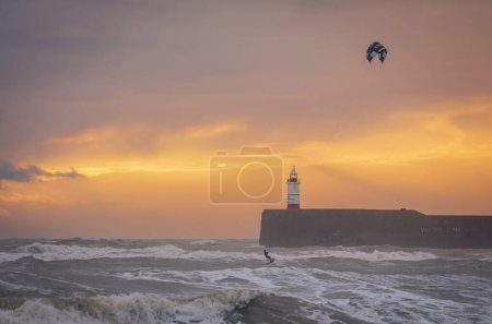 Téléchargez les photos : Kite surf sur mer agitée au coucher du soleil au phare de Newhaven et plage est Seaford est Sussex sud-est de l'Angleterre - en image libre de droit